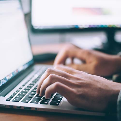 person's hands typing on a laptop