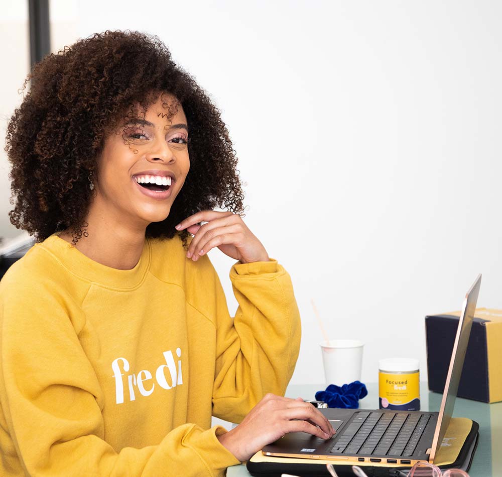 woman sitting in front of a laptop and smiling at the camera