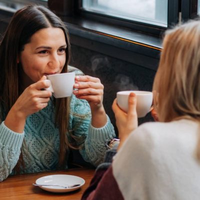 two women sitting at a table drinking coffee