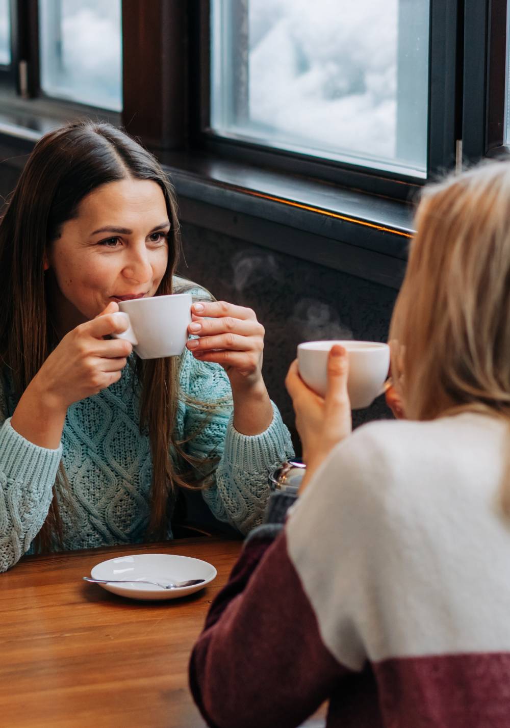 two women sitting at a table drinking coffee